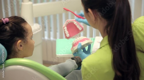 dentist showing girl how correctly to brush teeth