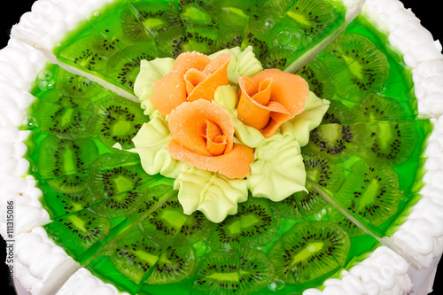 Portion cake with roses on kiwi close up