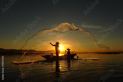 Murais de parede Fisherman of asian people at Lake in action when fishing during sunrise