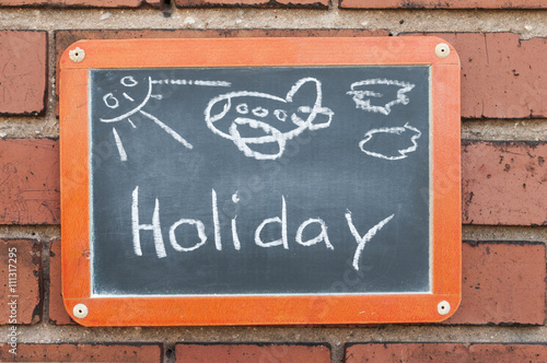 Tafel an einer Ziegelwand mit Text / Tafel an einer Ziegelwand mit Text Holiday. © ub-foto