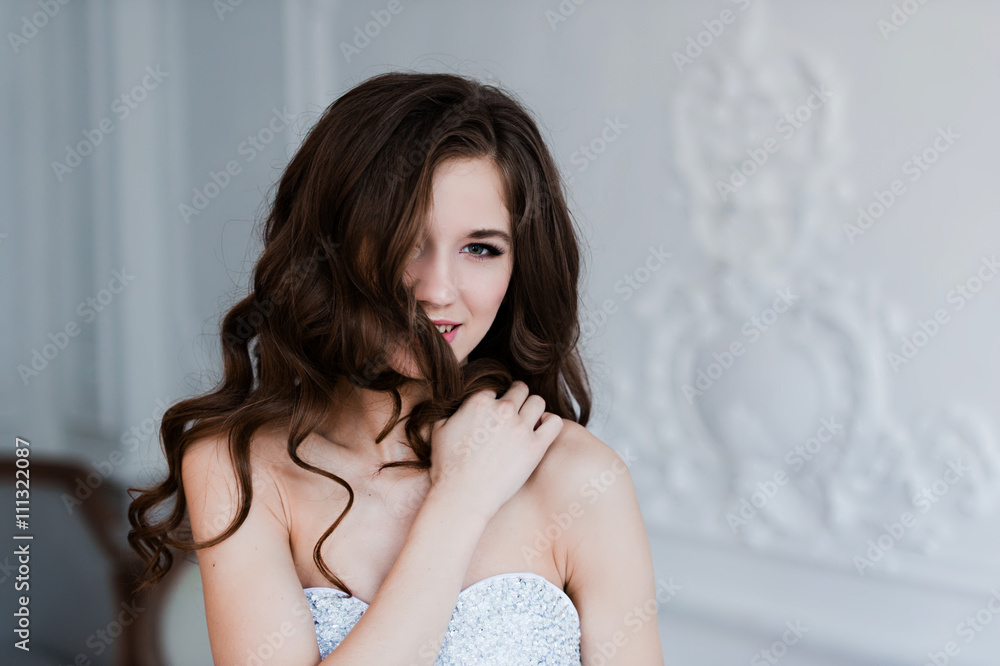 Naklejka premium Portrait of beautiful joyful curly bride, with fingers in her hair. Wedding hairstyle and make-up.
