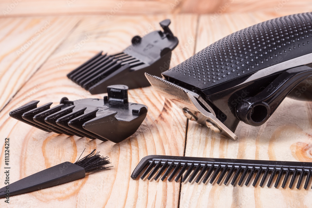 Obraz premium hair trimmer with attachment and a comb on wooden background
