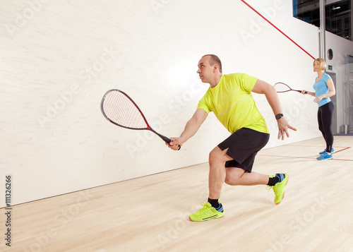 young caucasian man and woman playing squash.