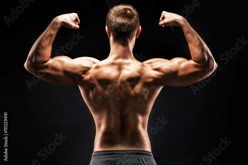Rear view of muscular young man showing back, biceps muscles