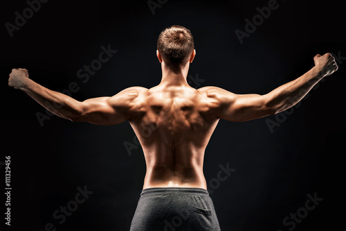 Rear view of muscular young man showing back, biceps muscles