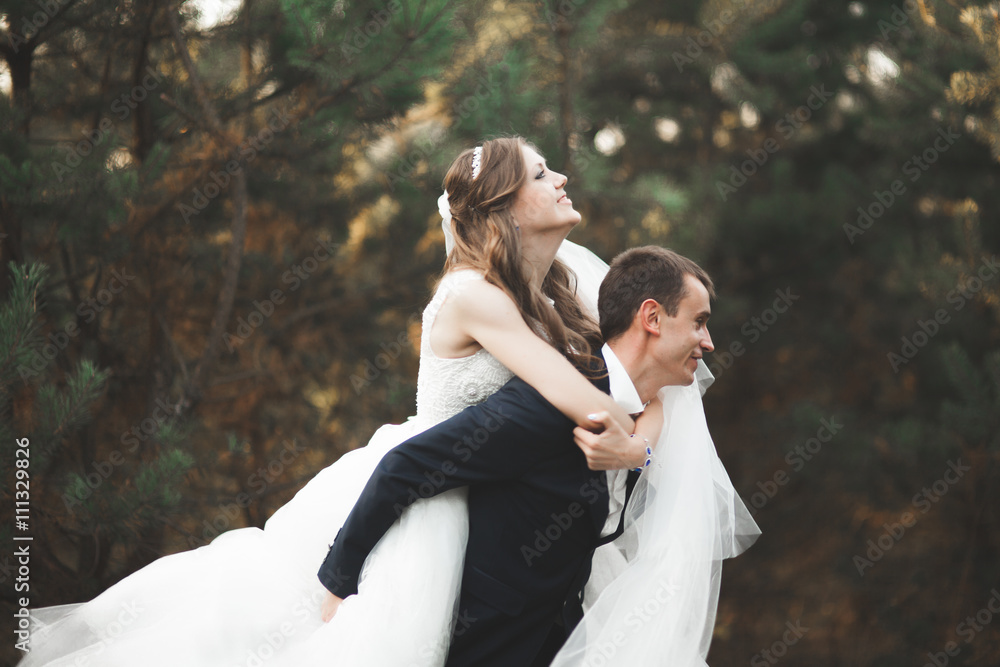 Elegant beautiful wedding couple posing in park at sunset Elegant beautiful wedding couple posing in park at sunset