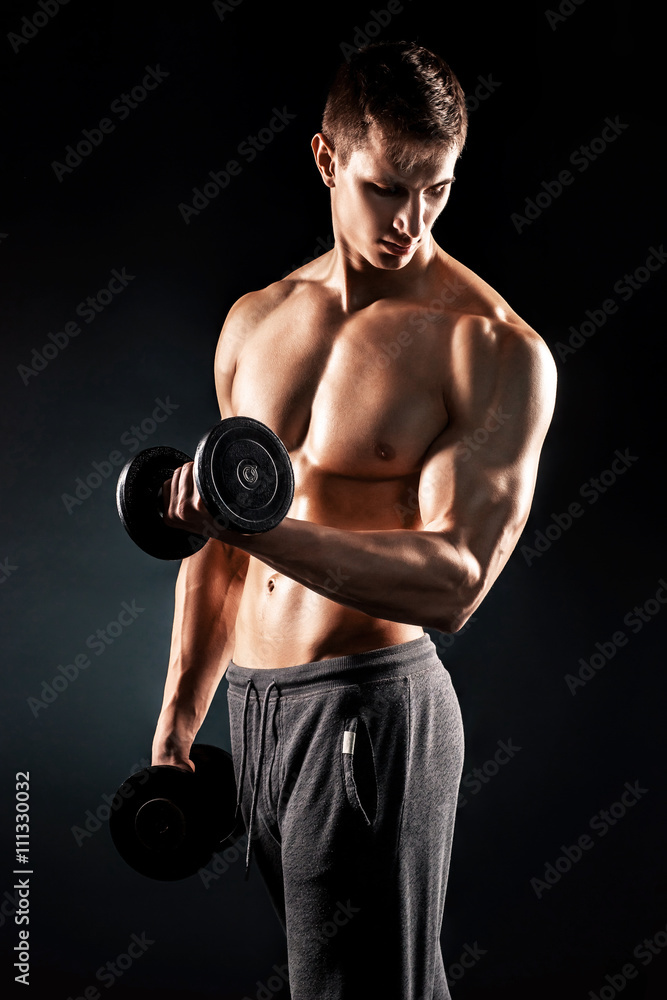 Athletic man showing muscular body and doing exercises with dumb