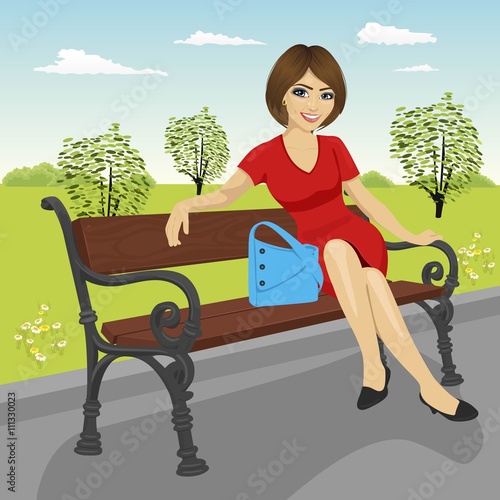 beautiful young model sitting on a bench in city park in summer and posing