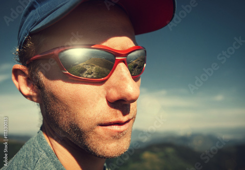Man in sun glasses with mountain mirorred in it photo