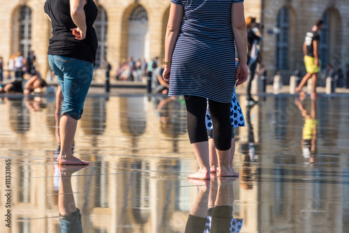 People having fun in a mirror fountain in Bordeaux, France