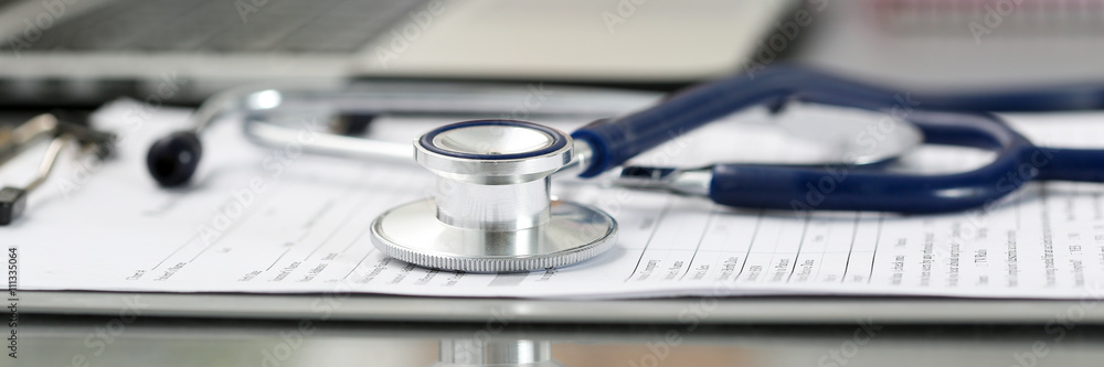 Stethoscope head lying on medical form on clipboard pad - obrazy, fototapety, plakaty 