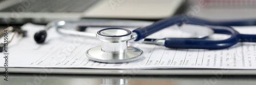 Stethoscope head lying on medical form on clipboard pad