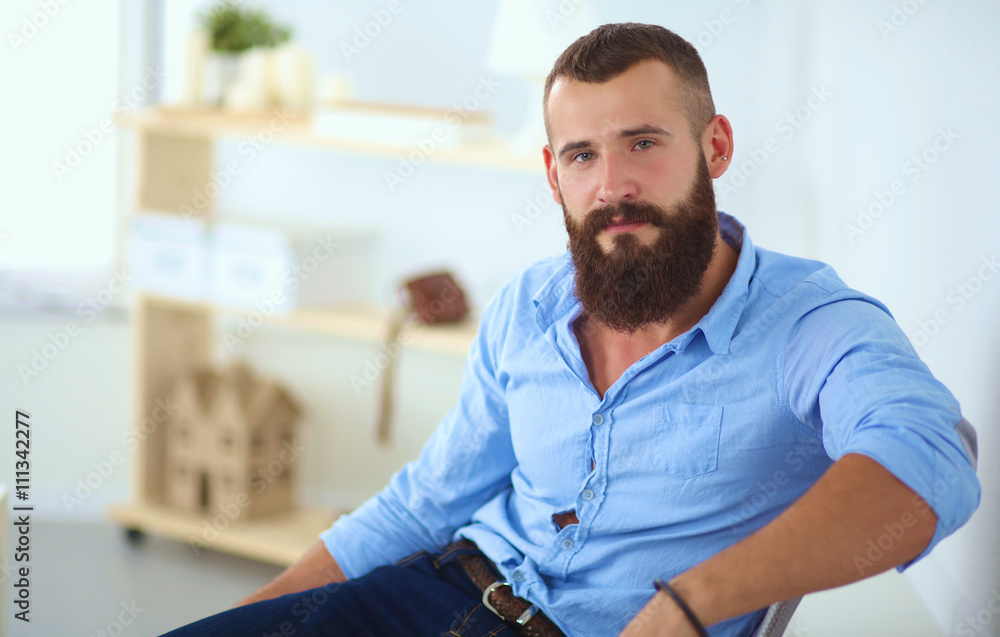Fototapeta premium Young businessman sitting on chair in office