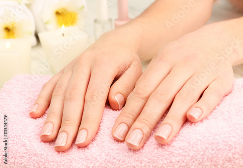 Spa concept. Woman hands with beautiful manicure and flowers on towel  close up