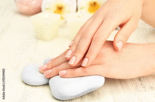 Spa concept. Woman hands with beautiful with pebbles on wooden background, close up