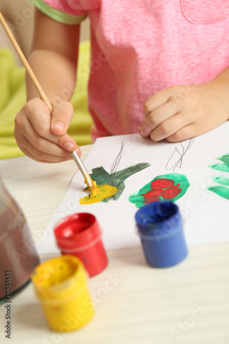 Child drawing tree with bright paints on paper, closeup