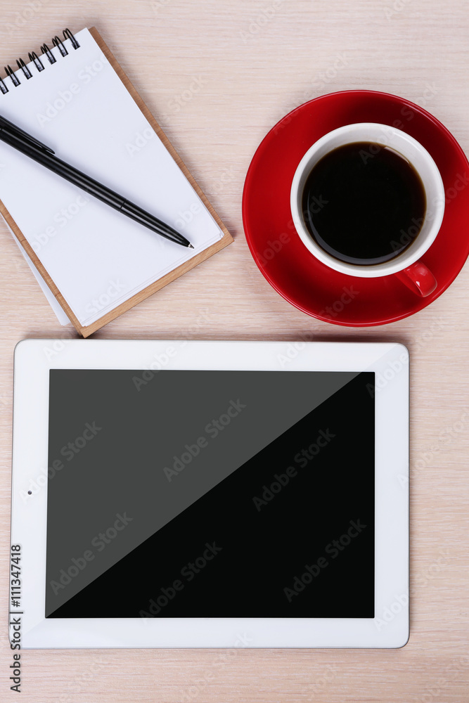 Tablet with cup of coffee and notepad on wooden table Tablet with cup of coffee and notepad on wooden table