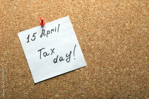 Tax day hand written reminder on April of 15th pinned to the board, top view
