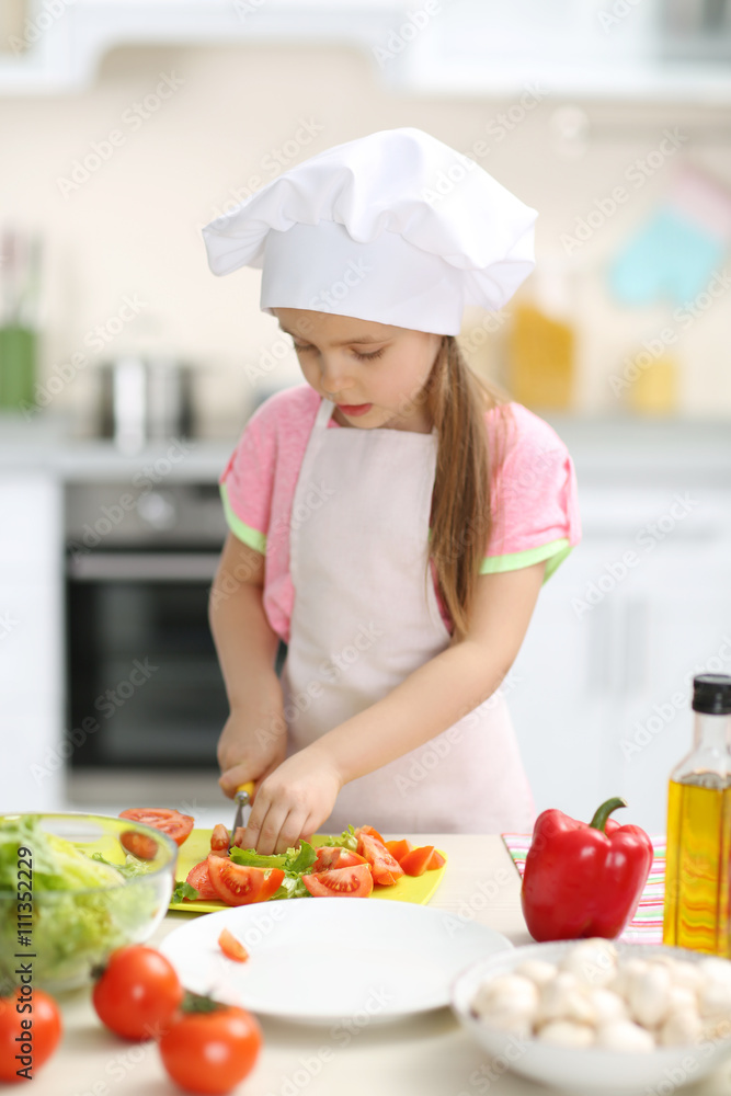 Little girl cutting vegetables for the salad in the kitchen Little girl cutting vegetables for the salad in the kitchen