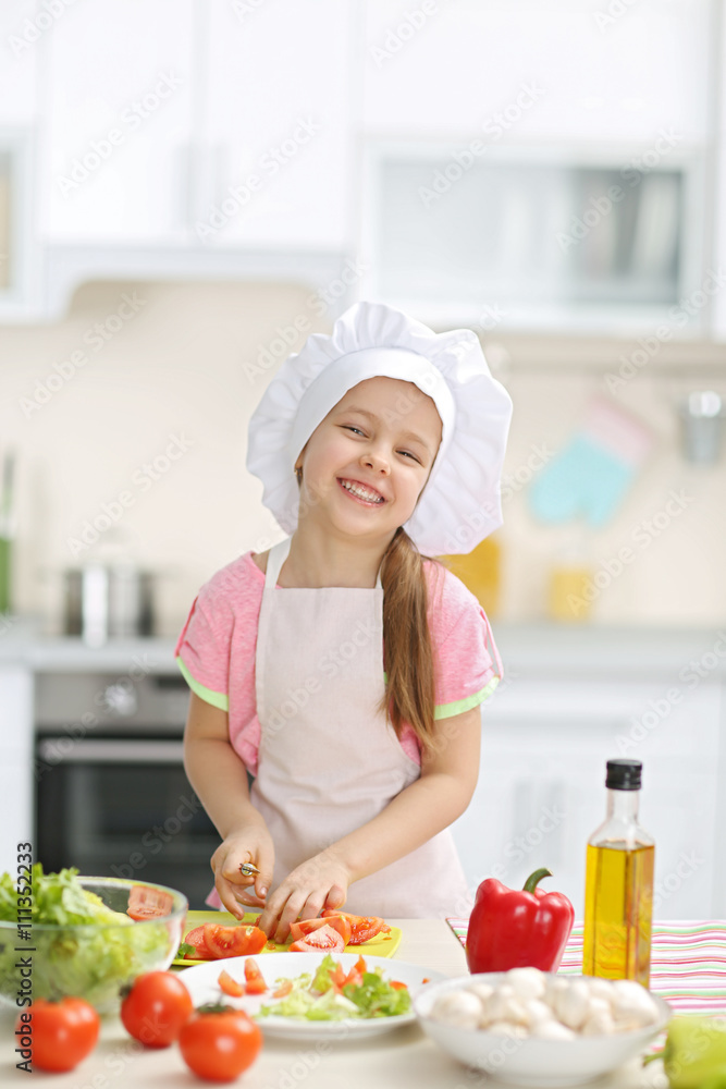 Little girl cutting vegetables for the salad in the kitchen Little girl cutting vegetables for the salad in the kitchen