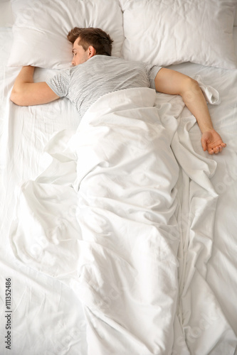 Young man sleeping alone in...
