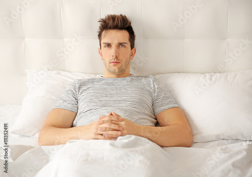 Sleepy young man in bed at ...