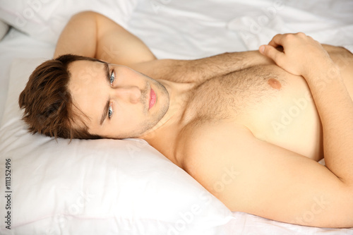 Young man lying in bed at home