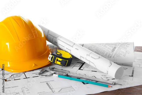 Construction blueprints with tools and helmet on white background