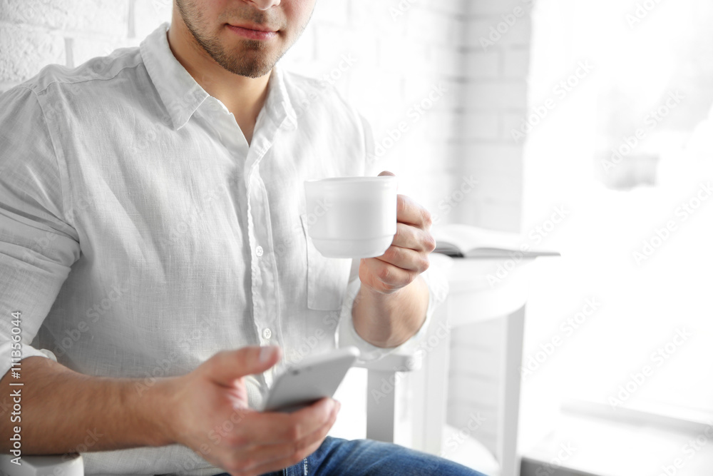 Man holding cellphone and cup of coffee, close up Man holding cellphone and cup of coffee, close up
