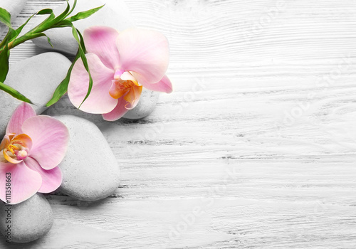 Spa stones, bamboo stack and orchid flowers on wooden background