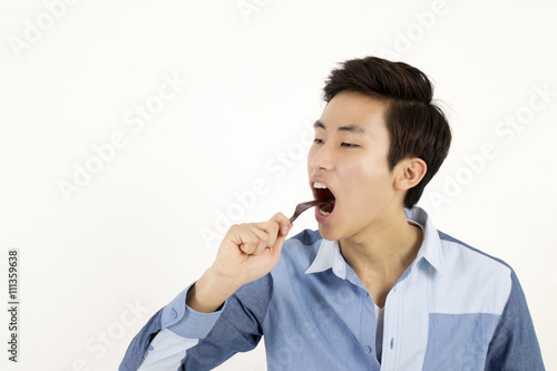 Asian man eat something with plastic fork
