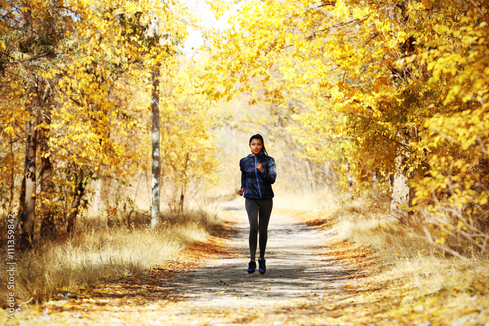 Young beautiful woman jogging in autumn park