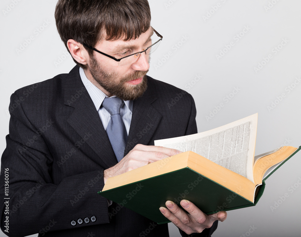 bearded businessman in a business suit and tie, reading a thick book bearded businessman in a business suit and tie, reading a thick book