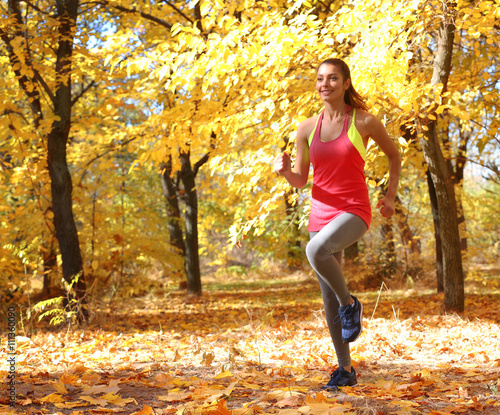 Young beautiful woman jogging in autumn park