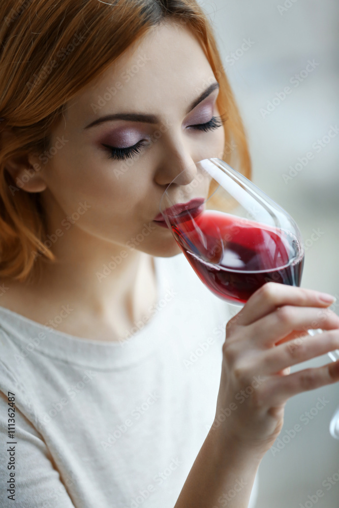 Young woman with glass of red wine on light blurred background Young woman with glass of red wine on light blurred background