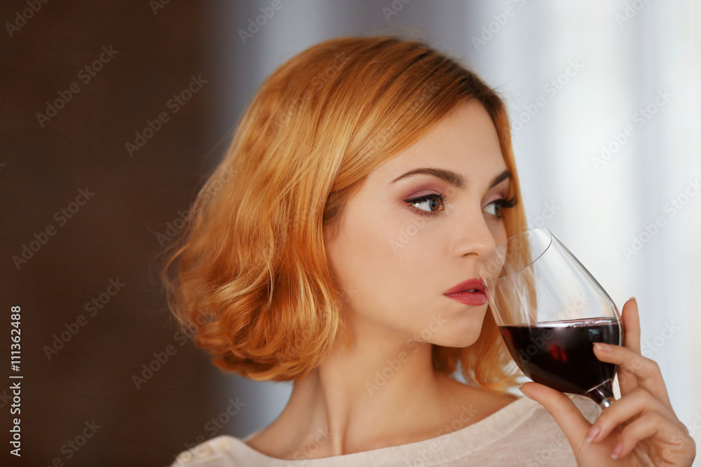 Young woman with glass of red wine on blurred background Young woman with glass of red wine on blurred background