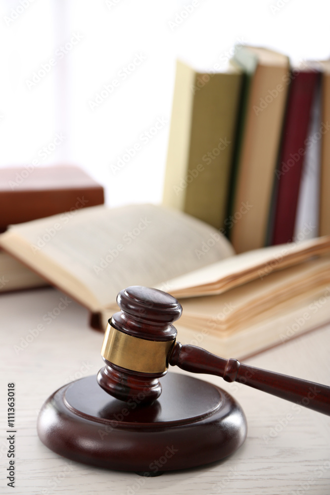 Gavel with books on wooden table closeup