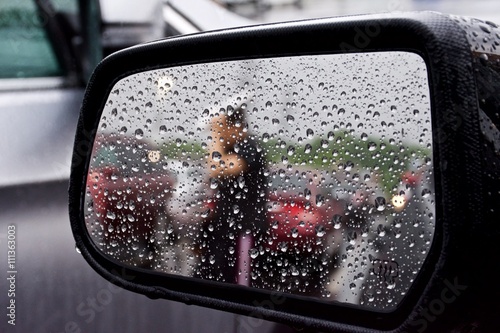 Looking into a car side mirror on a rainy day