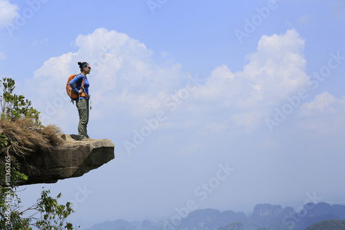 young woman hiker enjoy the view at mountain peak cliff