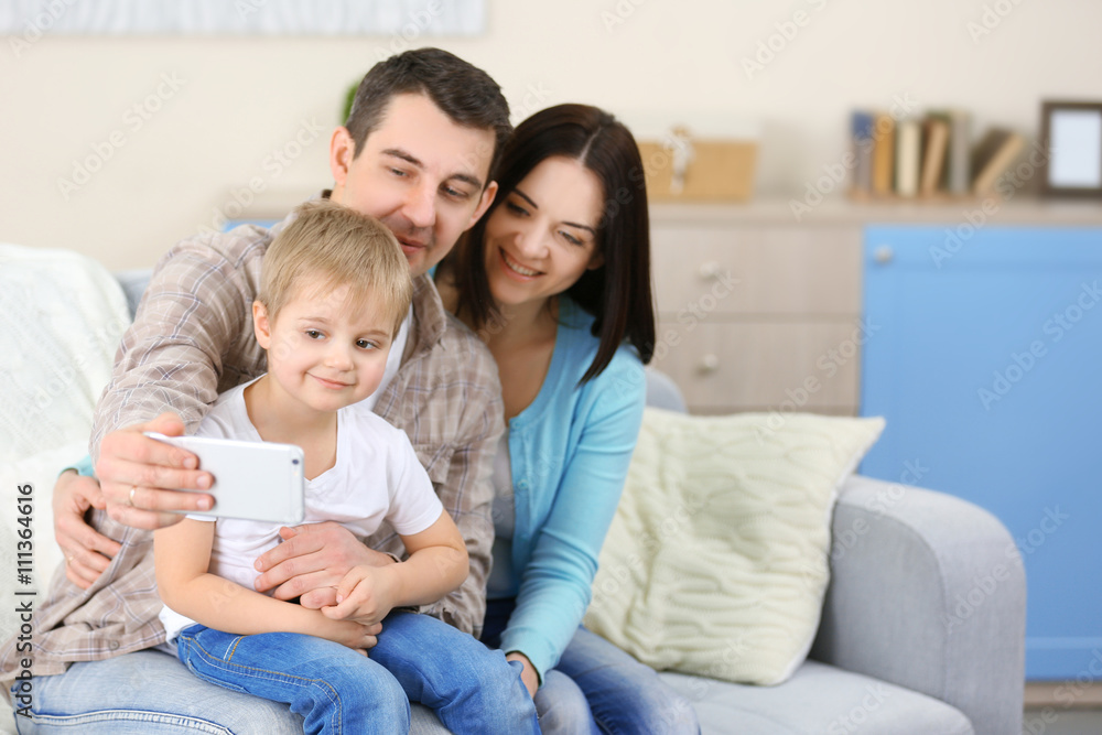 Happy family making selfie with mobile phone on couch, indoor Happy family making selfie with mobile phone on couch, indoor