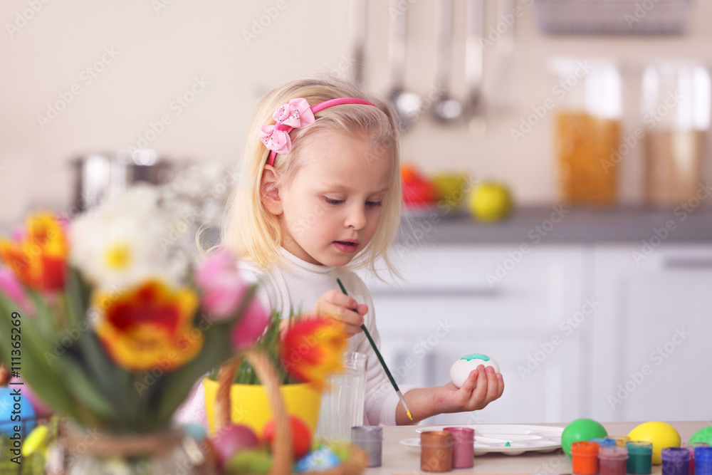 Little girl painting Easter eggs in the kitchen Little girl painting Easter eggs in the kitchen