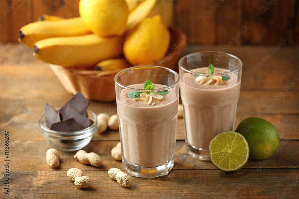 Fototapeta premium Fresh banana cocktail with peanuts and chocolate on wooden table