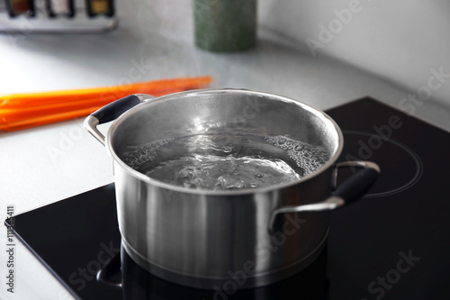 Boiling water in pan on electric stove in the kitchen photo
