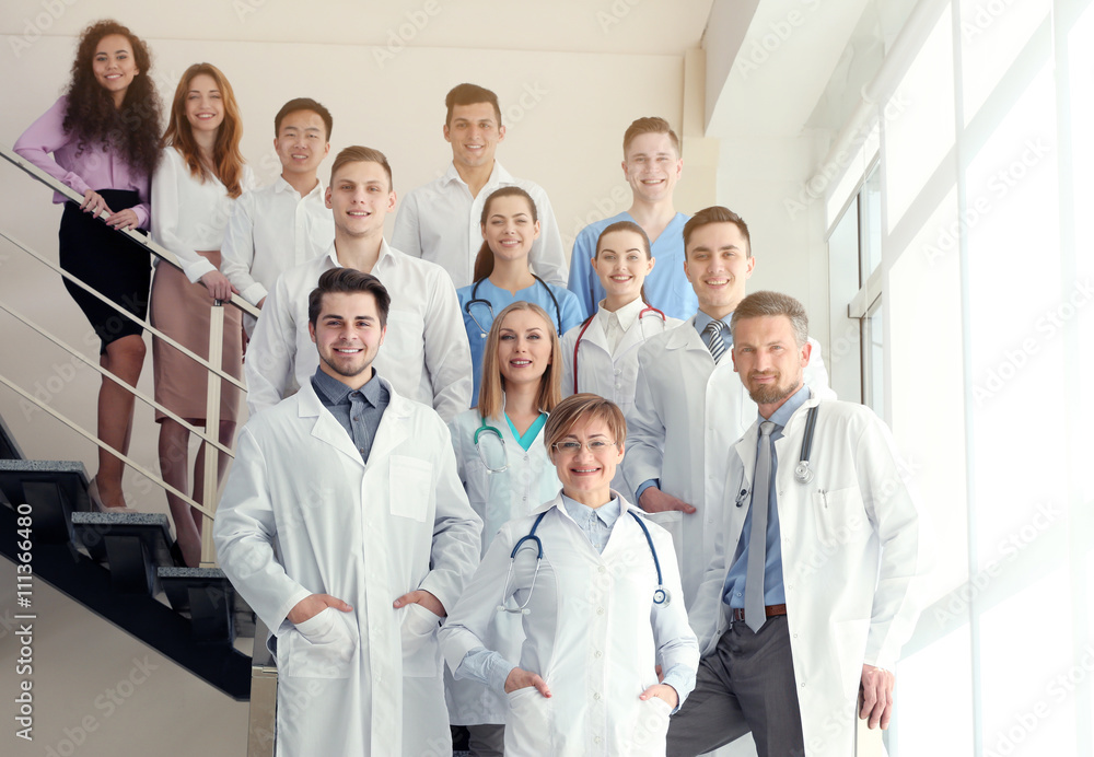A group of doctors and nurses standing on the stairs in the hospital, indoors A group of doctors and nurses standing on the stairs in the hospital, indoors