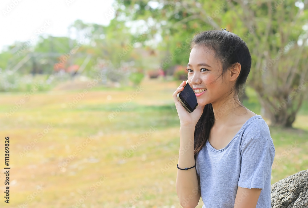 woman sitting on stone using a mobile telephone woman sitting on stone using a mobile telephone