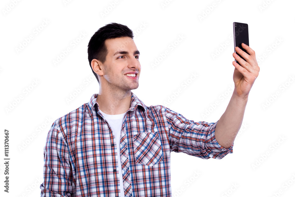 Cheerful selfie. Cheerful young man in shirt holding mobile phone and making photo of himself while standing against white isolated background Cheerful selfie. Cheerful young man in shirt holding mobile phone and making photo of himself while standing against white isolated background