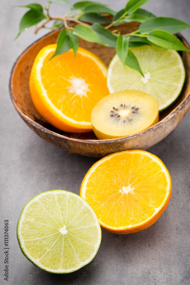 Mixed citrus fruit lemons, orange, kiwi, limes on a gray backgro Mixed citrus fruit lemons, orange, kiwi, limes on a gray backgro