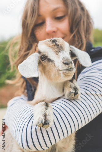 Beautiful girl with baby goat on farm photo