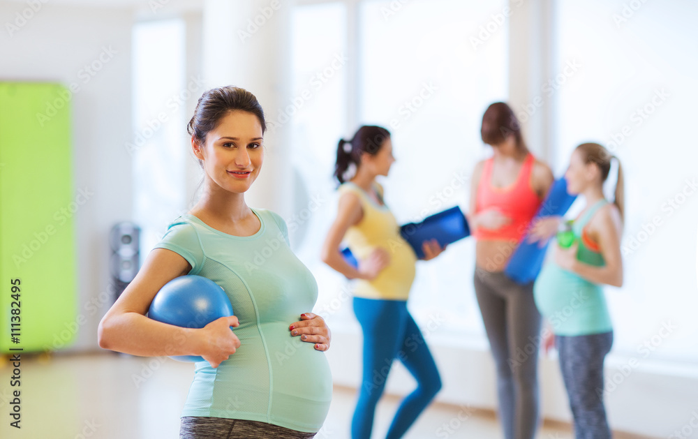 happy pregnant woman with ball in gym