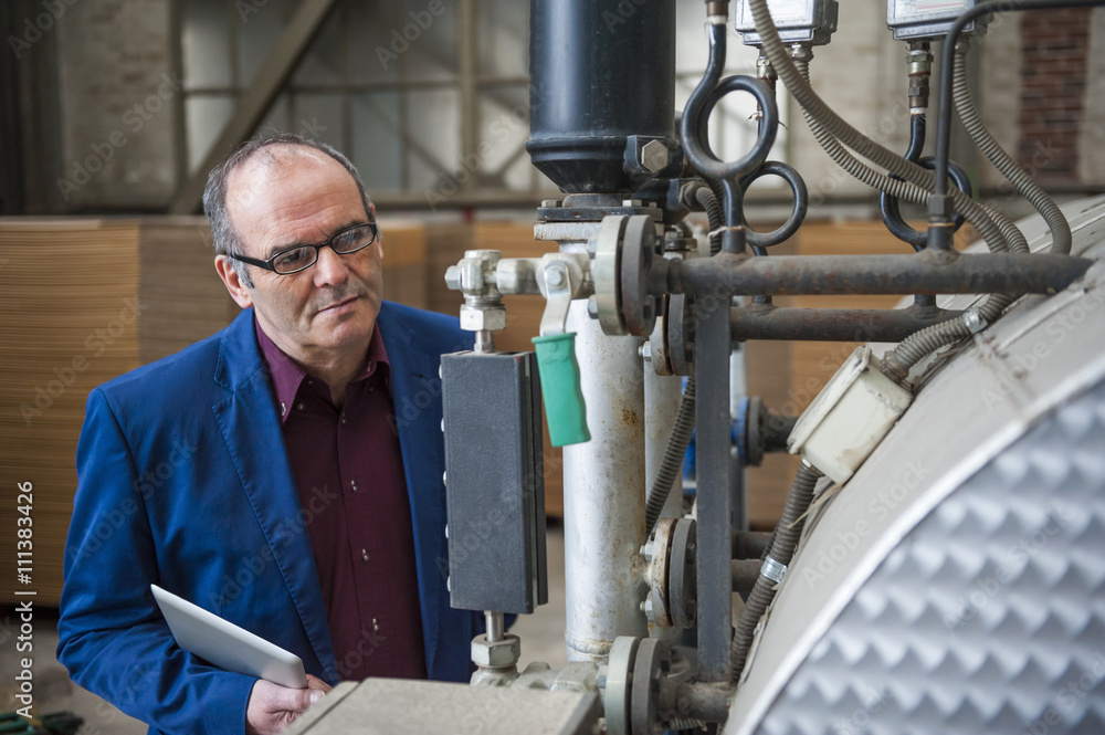 Manager in factory hall looking at machine Manager in factory hall looking at machine